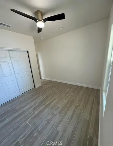 an empty room with wooden floor and fan