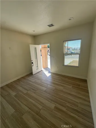 a view of an empty room with wooden floor and a window