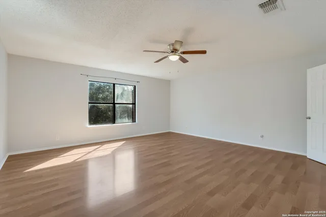 a view of room with hardwood floor and a ceiling fan