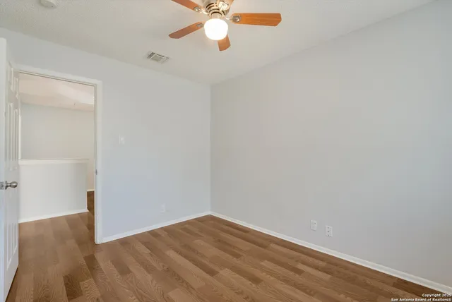 a view of a big room with wooden floor and a ceiling fan