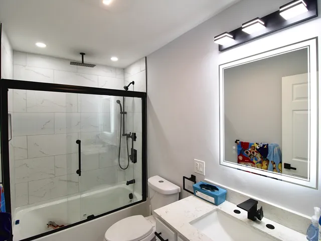 a bathroom with a bathtub shower sink vanity and toilet