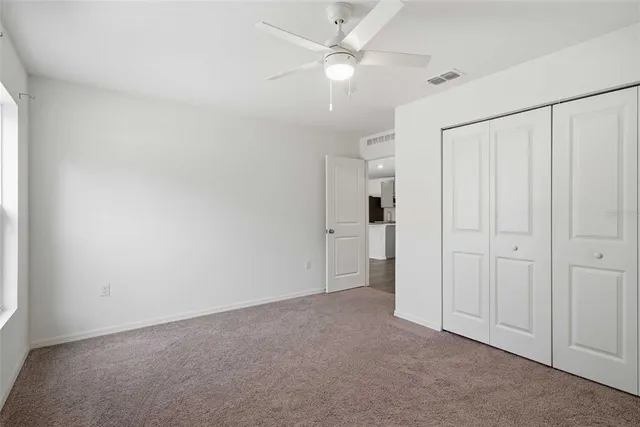 an empty room with windows and fan