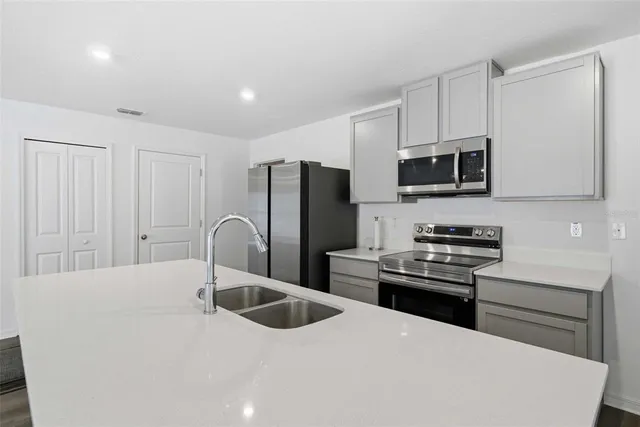 a kitchen with stainless steel appliances a microwave a sink a stove and cabinets