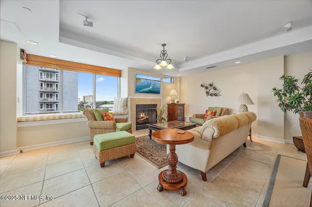 a living room with furniture a fireplace and a chandelier