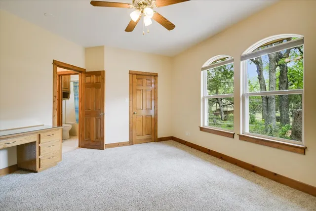 an empty room with windows and chandelier fan