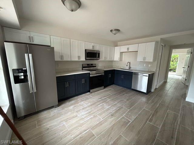Kitchen featuring stainless steel appliances, white cabinetry, and sink