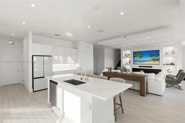 a kitchen with stainless steel appliances kitchen island a white counter space a sink and a refrigerator