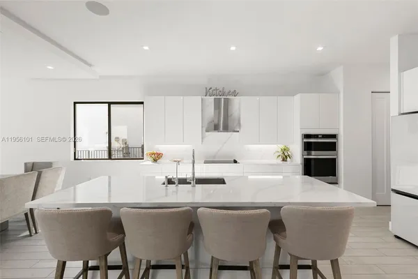 a kitchen with stainless steel appliances a table and chairs in it