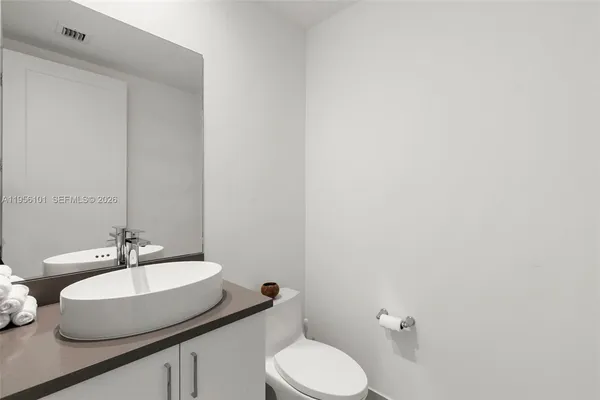 a bathroom with a granite countertop sink mirror vanity and toilet