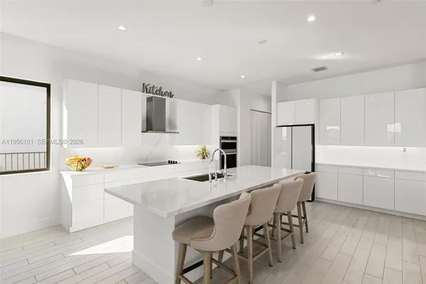 a kitchen with a dining table chairs and refrigerator
