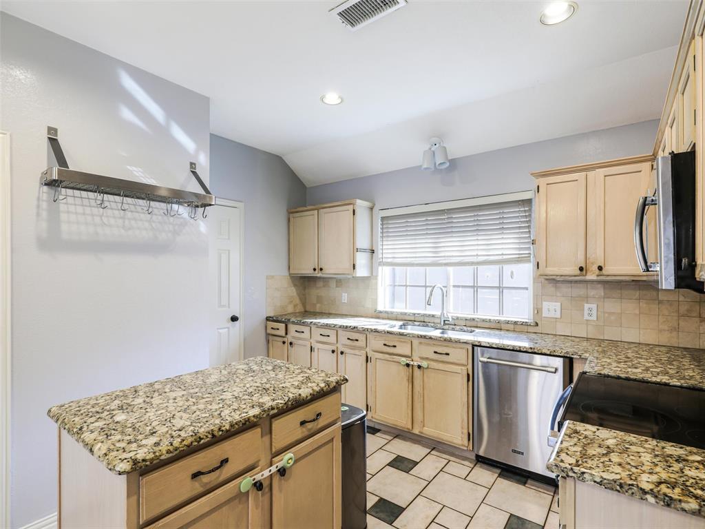 7836 Tournament Road Frisco, TX 75035 - Photo 11 of 23 Kitchen featuring wood cabinetry, a center island with a granite countertop, stainless steel appliances, and tile flooring