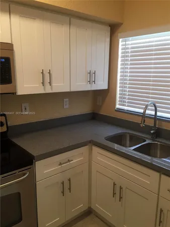 a kitchen with granite countertop white cabinets and a sink