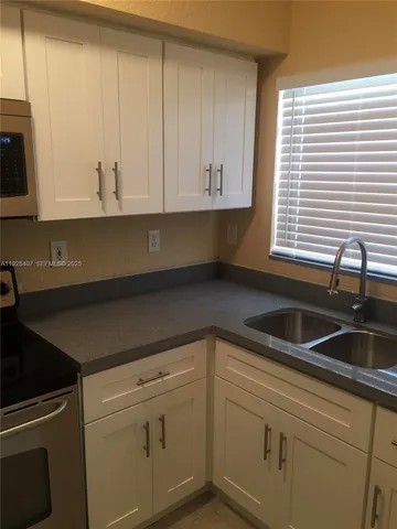 a kitchen with granite countertop white cabinets and a sink