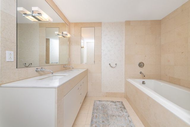 a bathroom with a tub sink and mirror