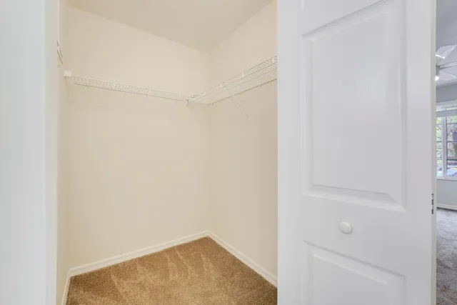 an empty room with windows and chandelier fan