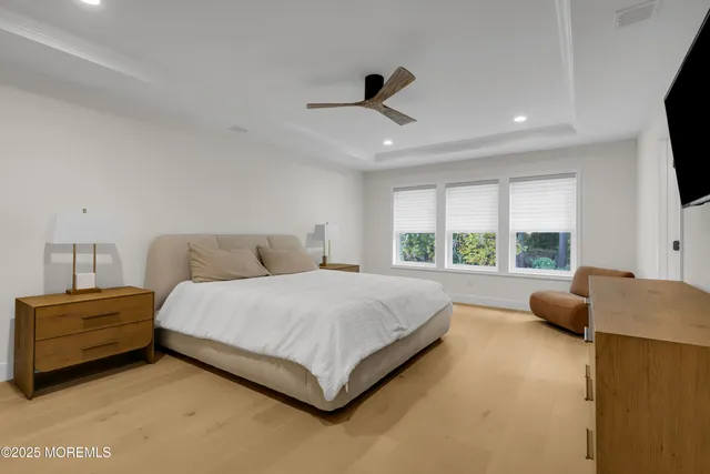 a spacious bedroom with a bed and a flat tv screen