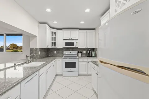 a kitchen with granite countertop white cabinets and white appliances
