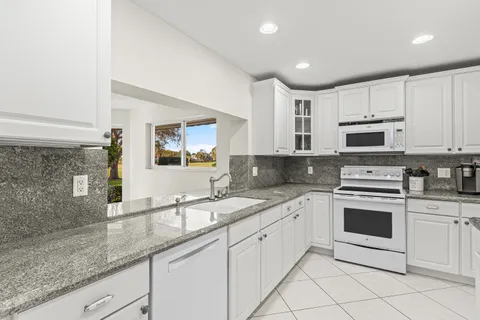 a kitchen with granite countertop white cabinets white stainless steel appliances with a sink and dishwasher