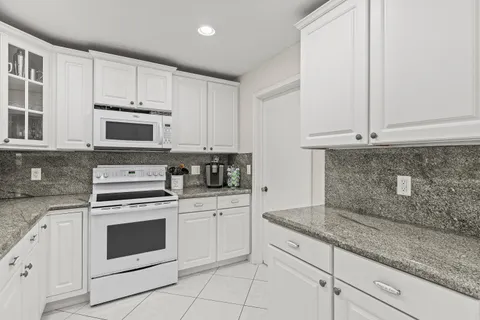 a kitchen with granite countertop white cabinets and white appliances