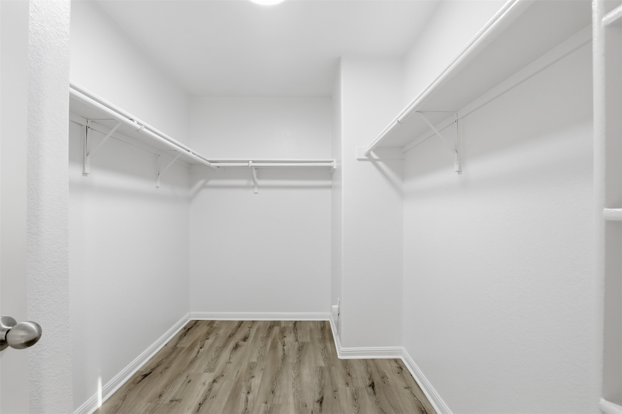 448 Nottingham Loop Kyle, TX 78640 - Photo 8 of 16 Walk-in closet featuring wood-finish flooring, white baseboards, white walls, overhead lighting, and white wire shelving