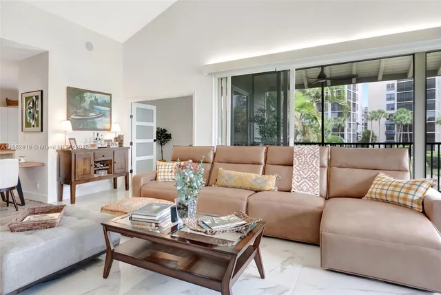a living room with furniture large windows and wooden floor