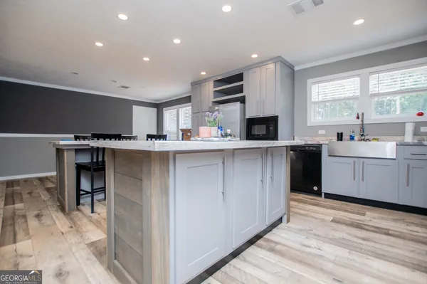 a kitchen with stainless steel appliances granite countertop a stove top oven a sink dishwasher and a refrigerator with wooden floor