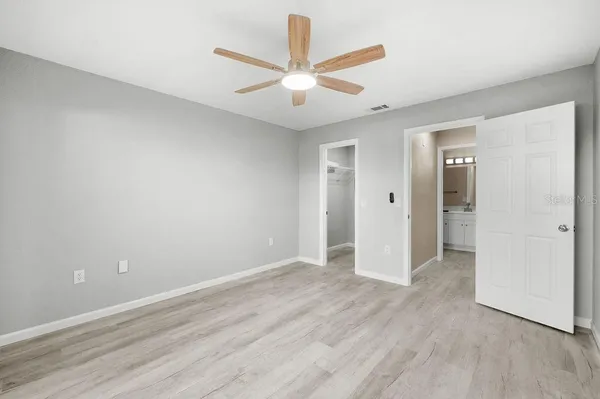 an empty room with wooden floor and ceiling fan