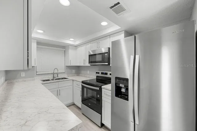 a kitchen with stainless steel appliances granite countertop a refrigerator a stove top oven a sink and dishwasher