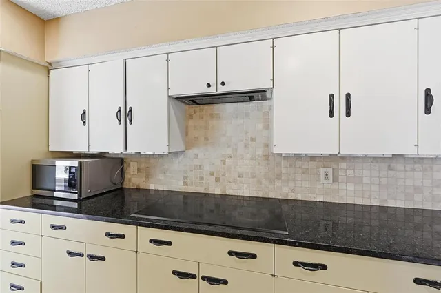 a kitchen with granite countertop a sink a refrigerator and cabinets