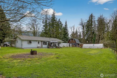 a house that has a big yard with plants and large trees