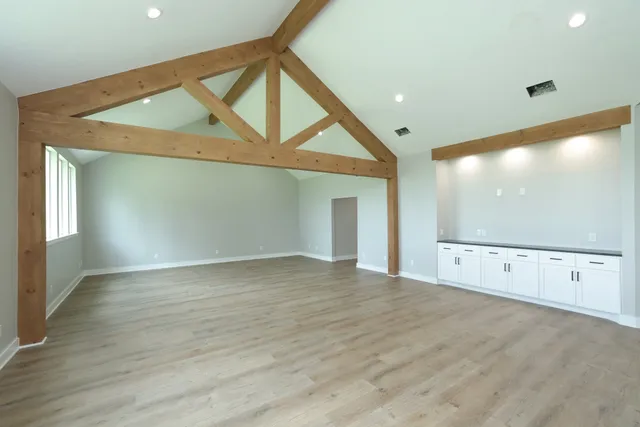 a view of an empty room with wooden floor and windows