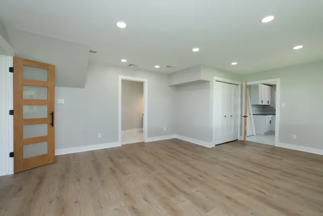 an empty room with wooden floor & windows and bathroom