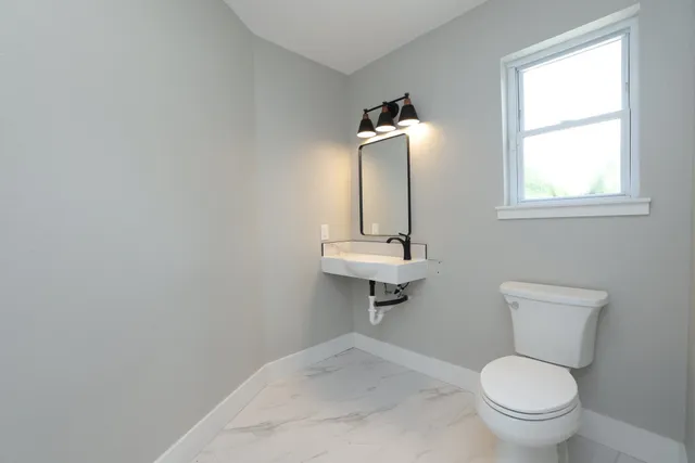 a bathroom with a toilet a sink and a window