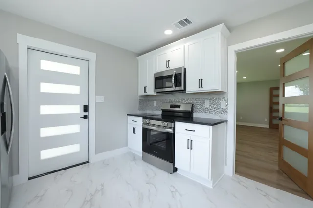 a kitchen with granite countertop white cabinets and stainless steel appliances