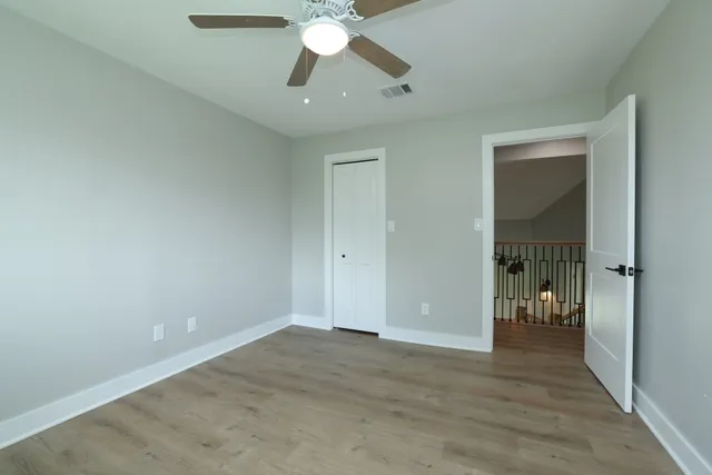 wooden floor in an empty room with a chandelier fan