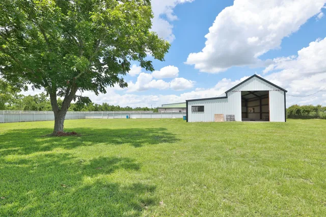 a view of a house with a big yard and large tree