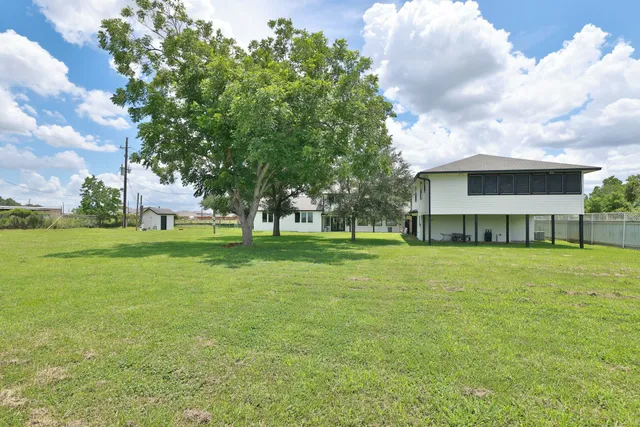 a view of a house with a big yard and large trees