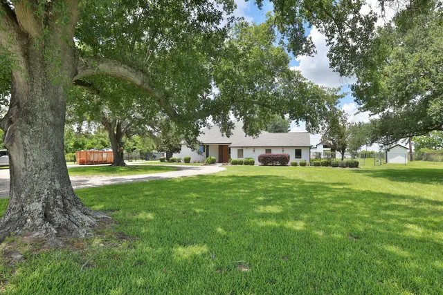 a view of a house with a big yard and large trees