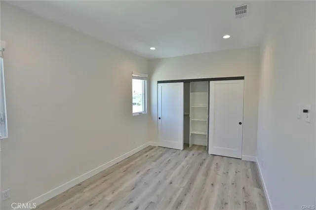 a view of an empty room with wooden floor and closet
