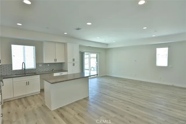 a kitchen with a sink cabinets wooden floor and a window