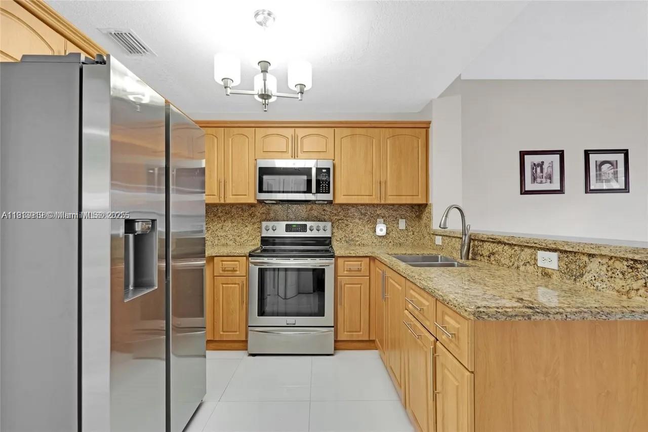 8422 Northwest 140th Terrace, Unit 3608 Miami Lakes, FL 33016 - Photo 13 of 23 a kitchen with stainless steel appliances granite countertop a sink stove and refrigerator