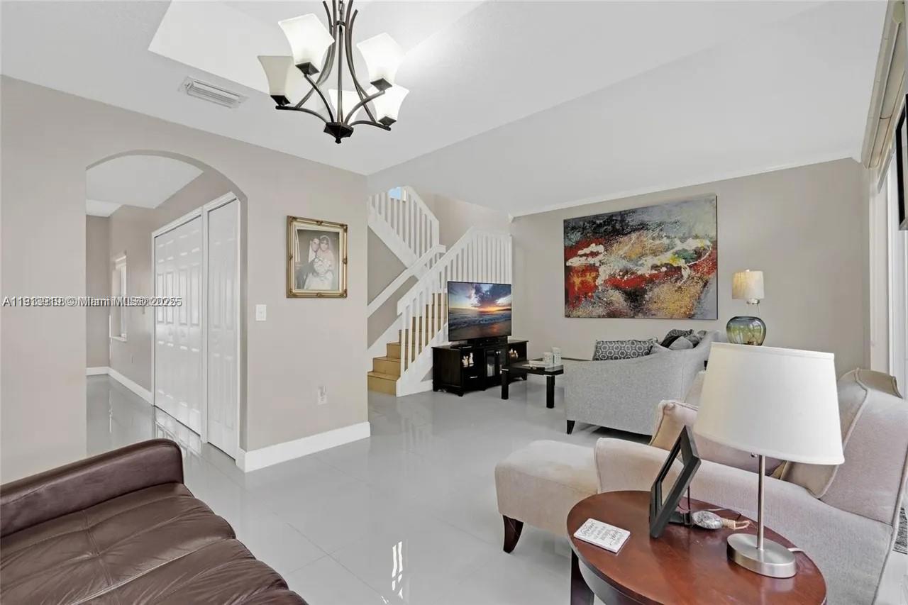 8422 Northwest 140th Terrace, Unit 3608 Miami Lakes, FL 33016 - Photo 9 of 23 a living room with furniture and a chandelier