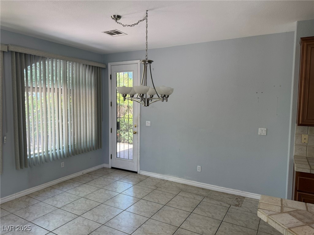 985 Prestwick Street Las Vegas, NV 89145 - Photo 12 of 27 Unfurnished dining area with a chandelier and light tile patterned floors