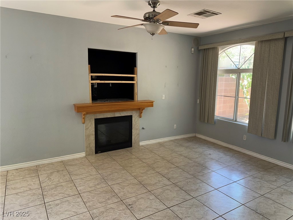 985 Prestwick Street Las Vegas, NV 89145 - Photo 24 of 27 Unfurnished living room with a tiled fireplace, a ceiling fan, and tile patterned floors