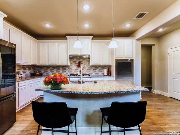 a kitchen with stainless steel appliances kitchen island a table chairs in it and wooden floors