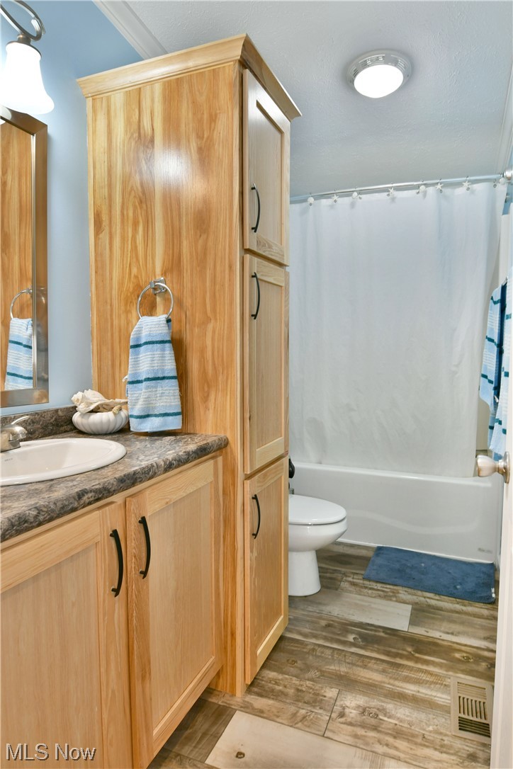 1570 Kale Adams Road Southwest Warren, OH 44481 - Photo 11 of 34 Full bathroom featuring toilet, wood-type flooring, shower / tub combo with curtain, ornamental molding, and large vanity