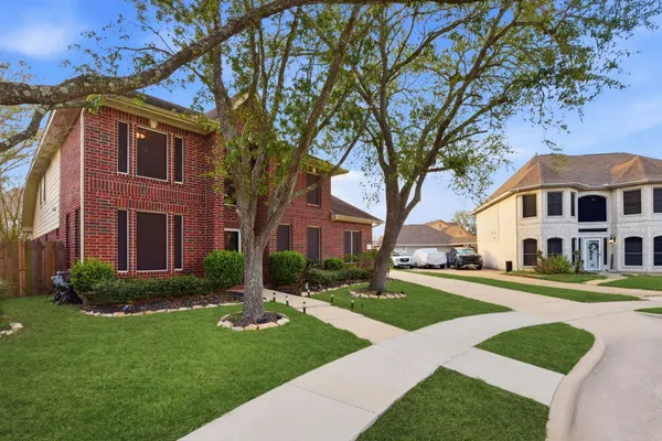 a view of a big yard in front of a brick house