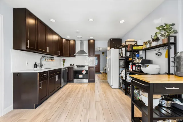 a kitchen with stainless steel appliances kitchen island granite countertop a refrigerator a sink dishwasher a stove and a dining table with wooden floor