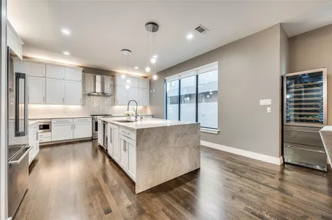 a large kitchen with stainless steel appliances granite countertop a lot of counter space and wooden floors