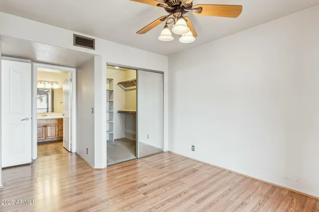an empty room with wooden floor closet and windows